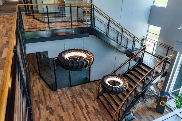 Overhead view of black steel, oak, and wire railing staircase in office lobby