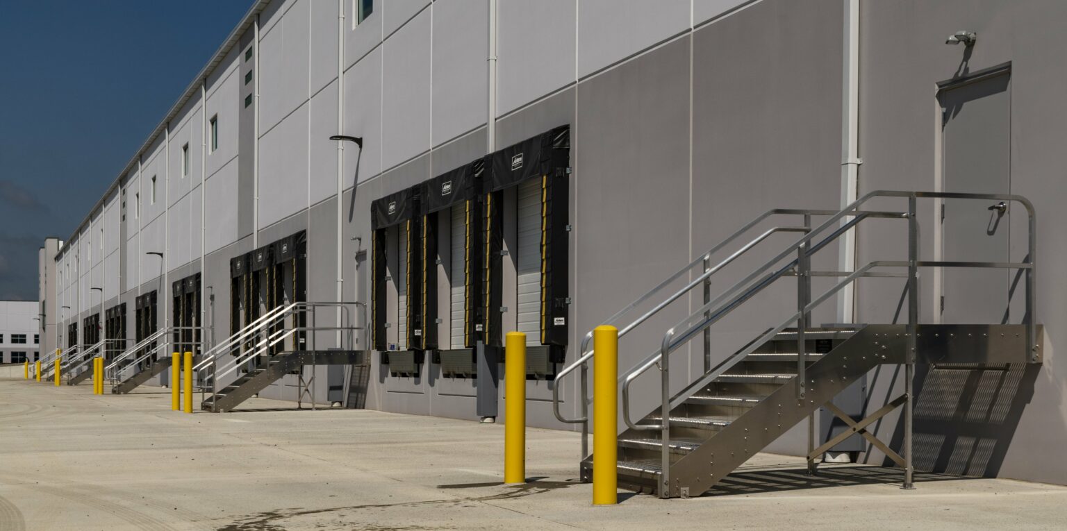 Wide view of bollards protecting multiple Aluminum dockstairs installed along side of warehouse