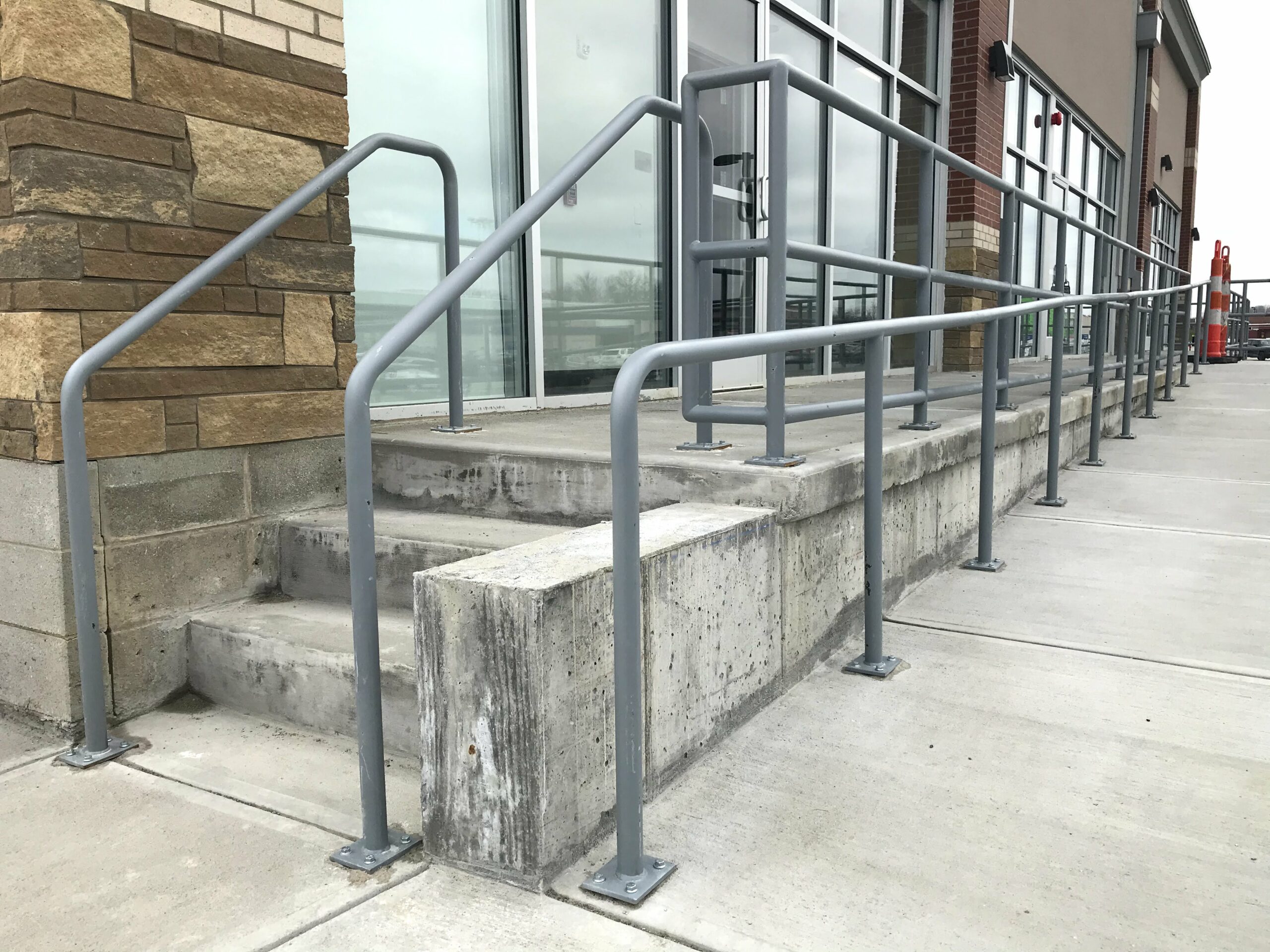 Tight left view of gray steel ramp and sidewalk railing outside retail offices