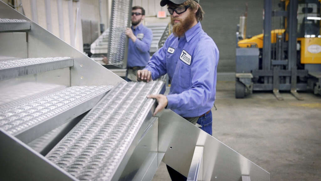 Workers assembling grip strut treads on aluminum dock stair