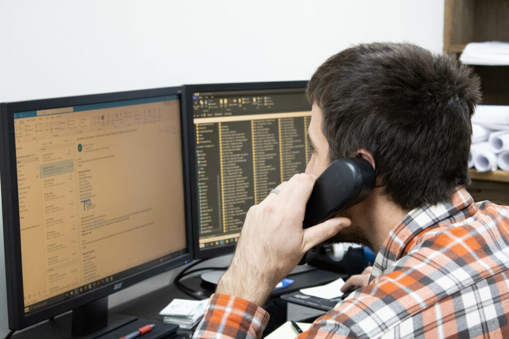 Project manager on the phone looking at computer screen