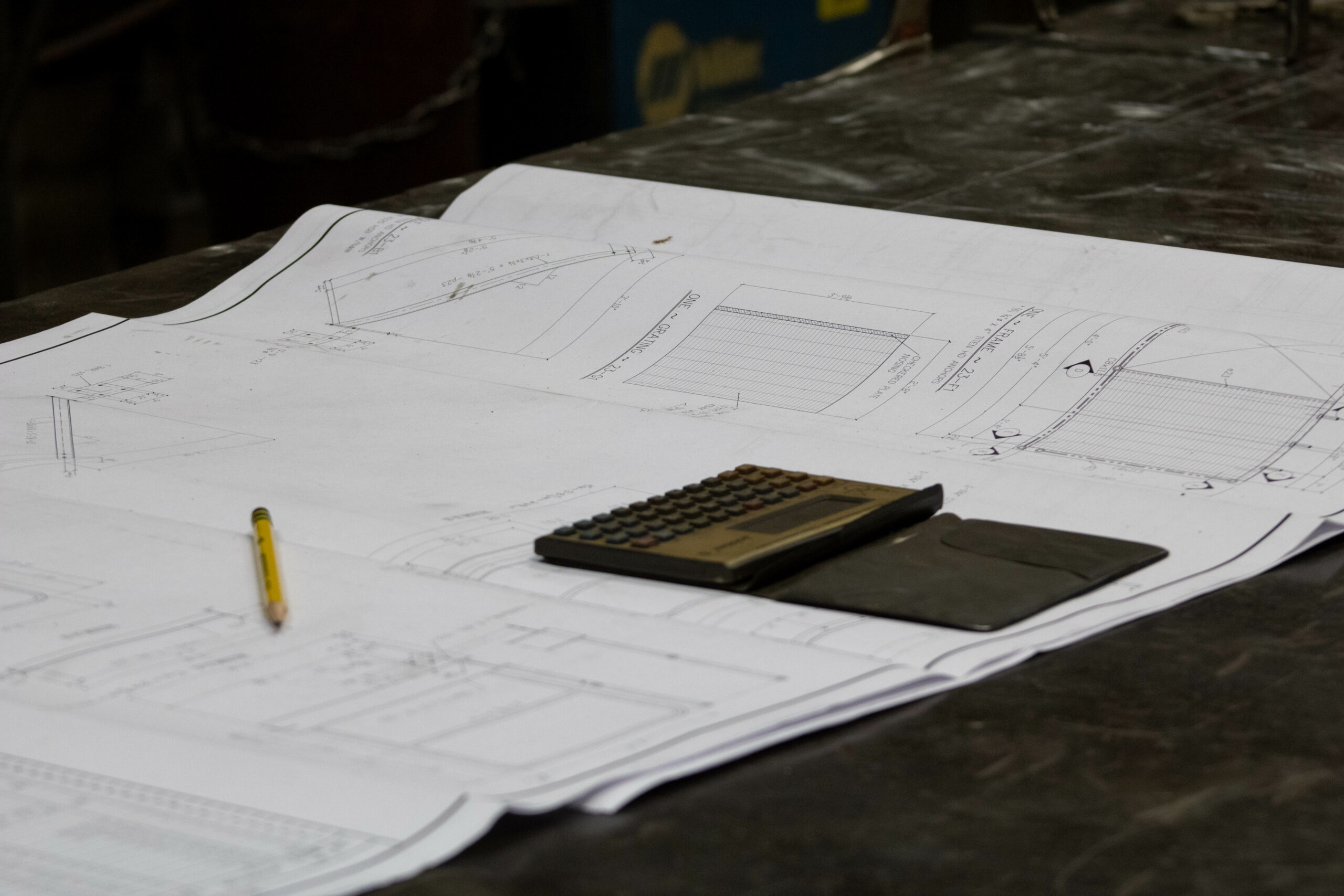 Shop drawings on a table with calculator and pencil