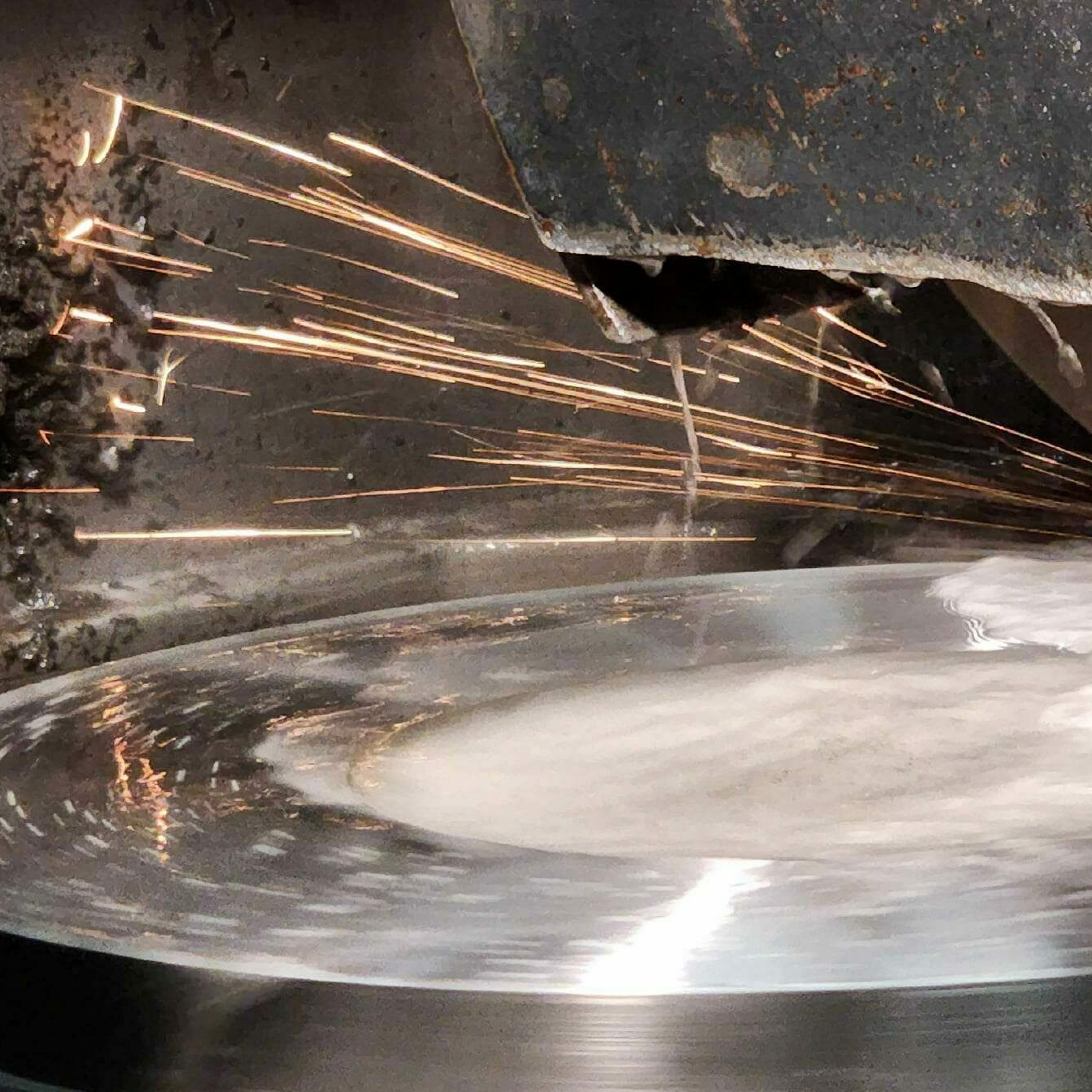 Sparks flying from steel tooling on Blanchard grinder
