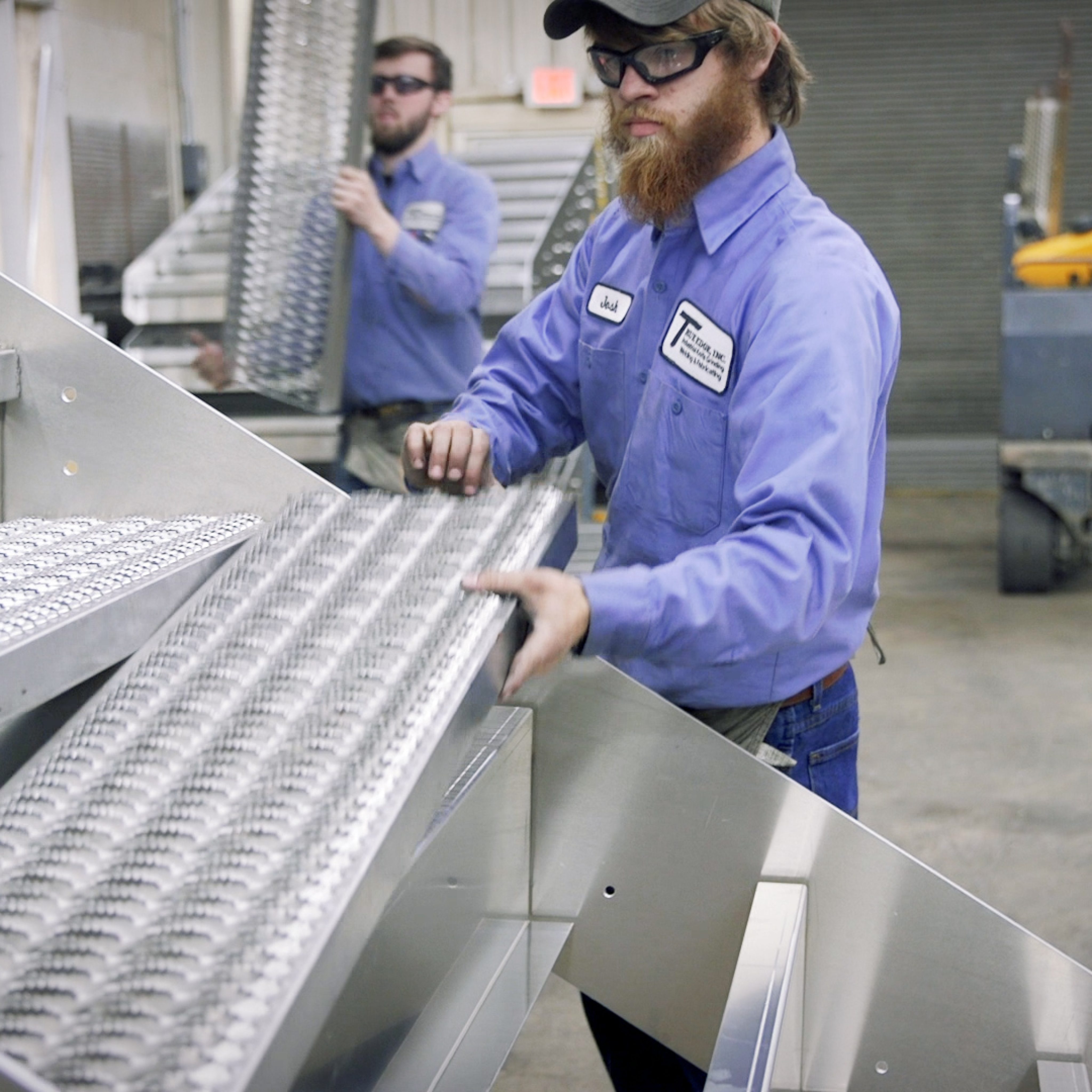 Workers assembling grip strut treads onto aluminum dock stair